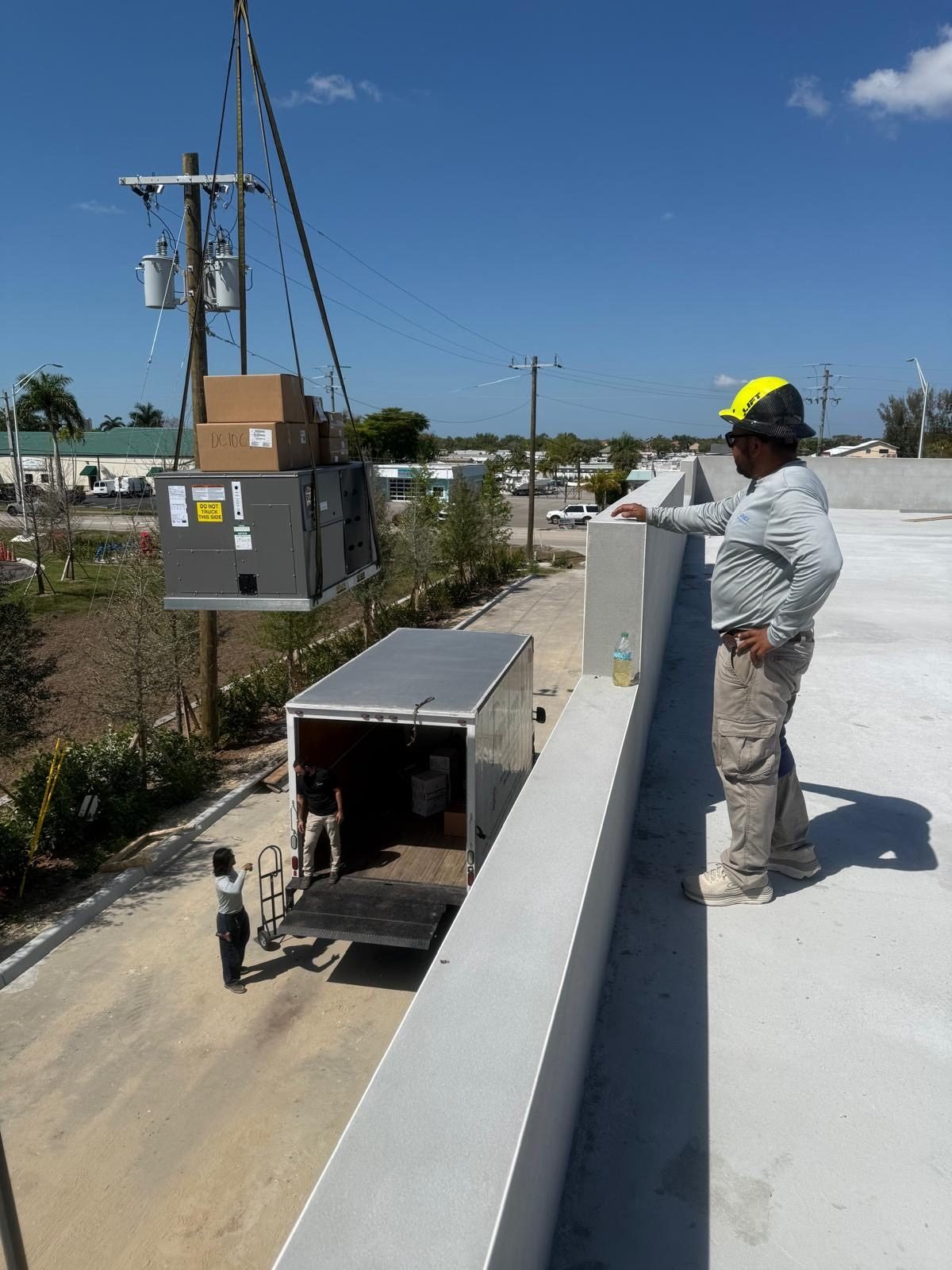 Jorge & Josue bringing a package unit up the side of the building.