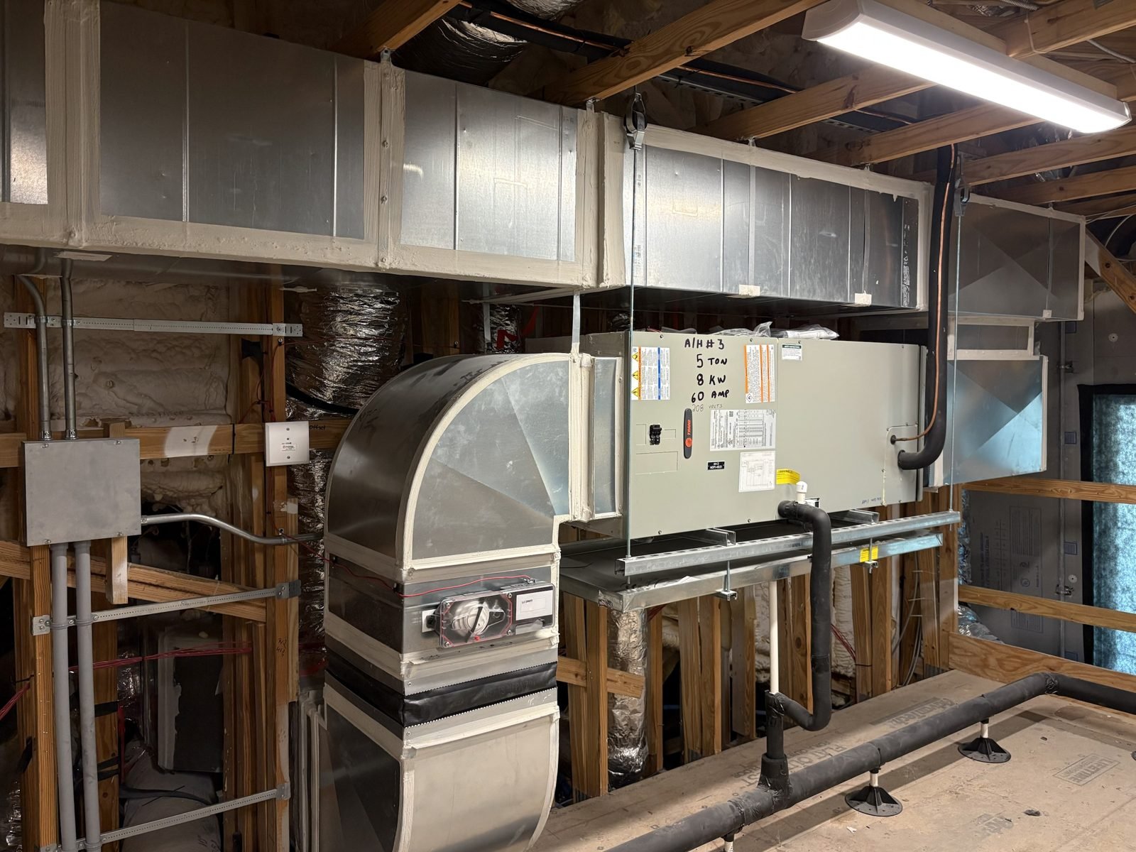 Same mechanical room, other angle. Trunk cross broken, sealed on every seam, hung level, nothing resting on a stud.